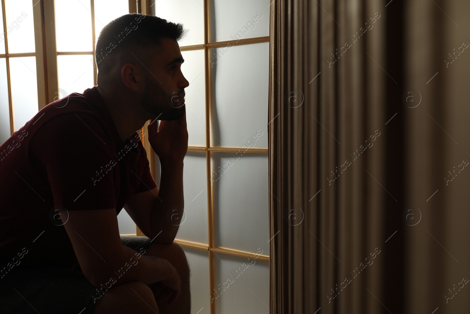 Photo of Silhouette of sad man at home. Space for text