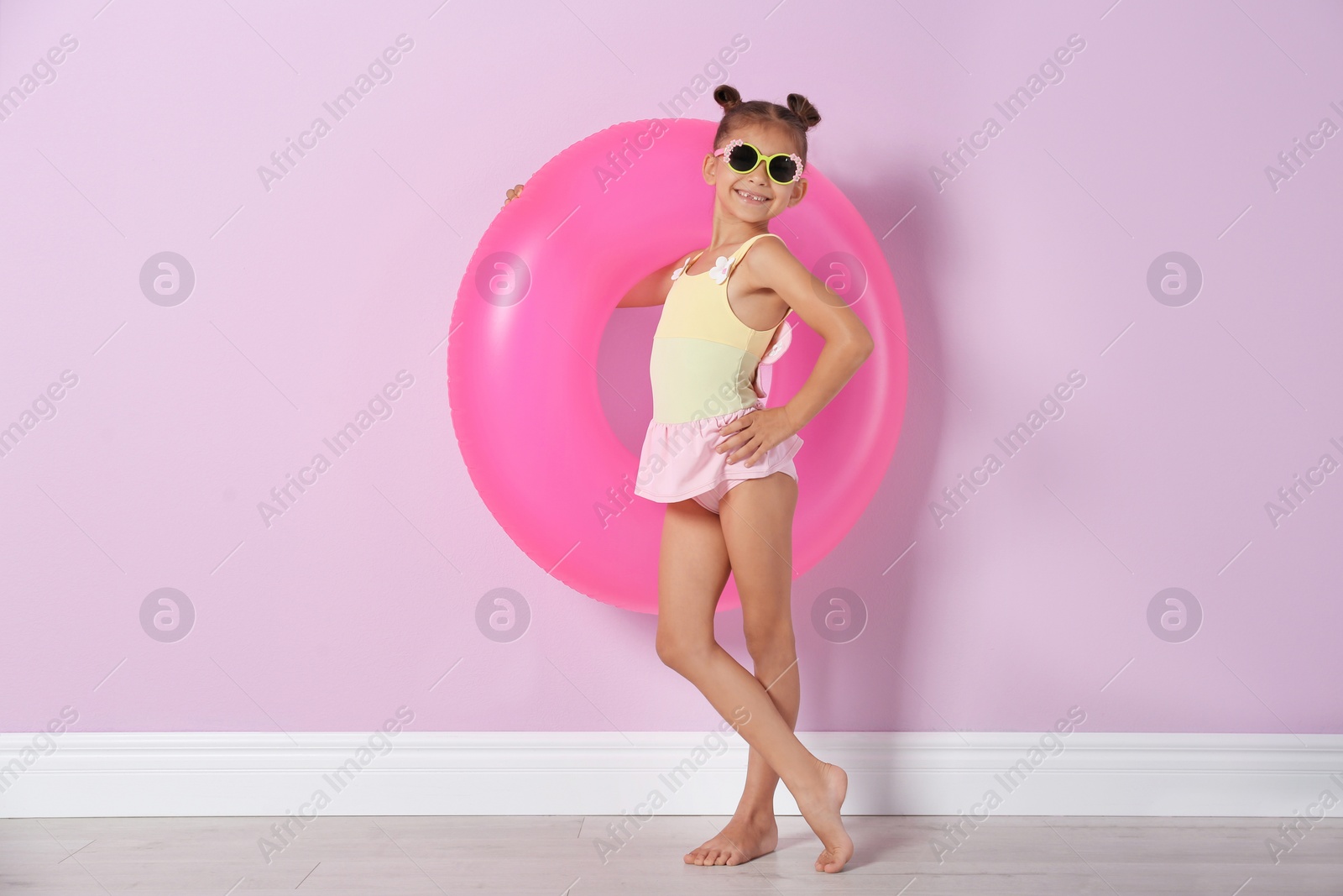 Photo of Cute little girl with inflatable ring near color wall