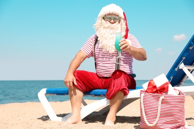 Photo of Authentic Santa Claus with cocktail resting on lounge chair at resort