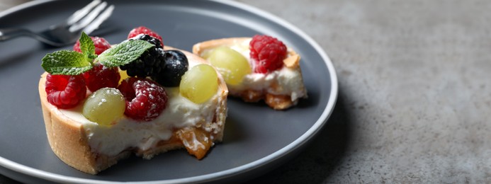 Delicious tartlet with fresh berries on grey table, closeup. Banner design