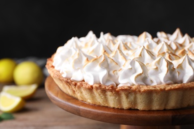 Photo of Stand with delicious lemon meringue pie on wooden table, closeup