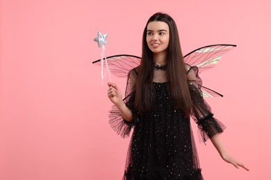 Photo of Beautiful girl in fairy costume with wings and magic wand on pink background, space for text