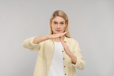 Photo of Woman showing time out gesture on grey background. Stop signal