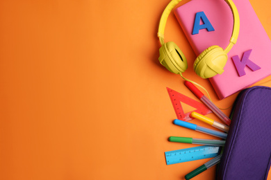 Flat lay composition with book and stationery on orange background. Space for text