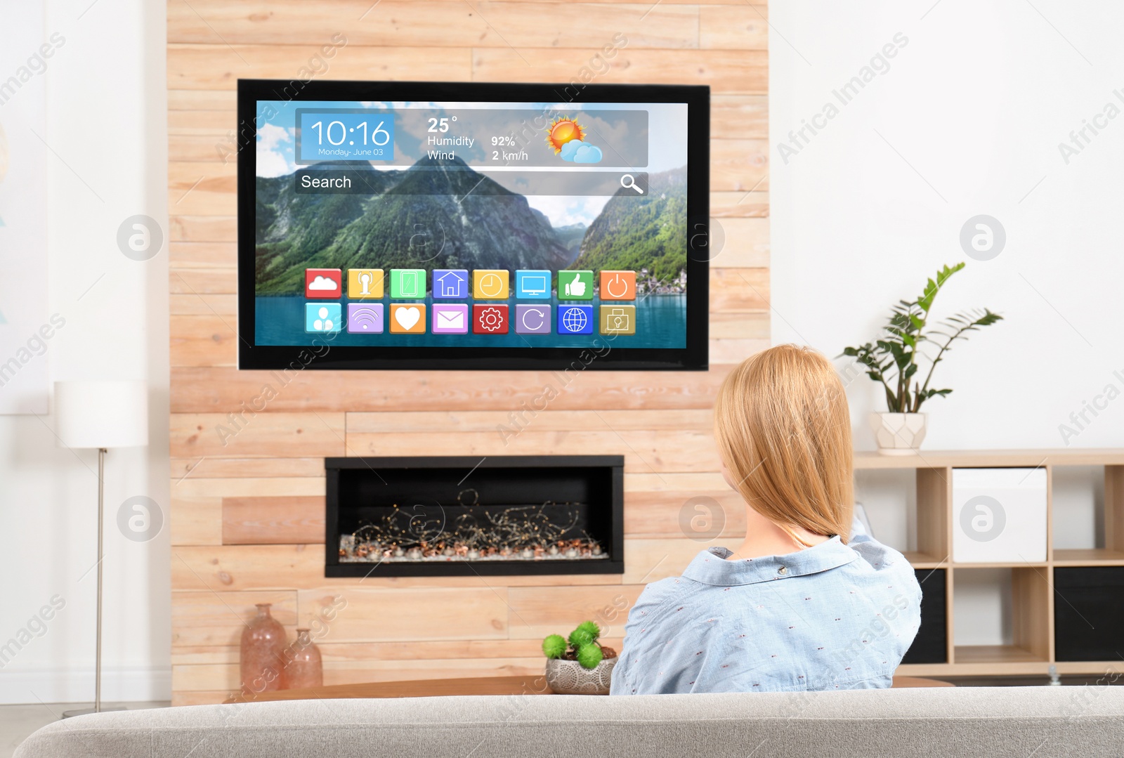 Image of Woman watching smart TV on sofa in living room