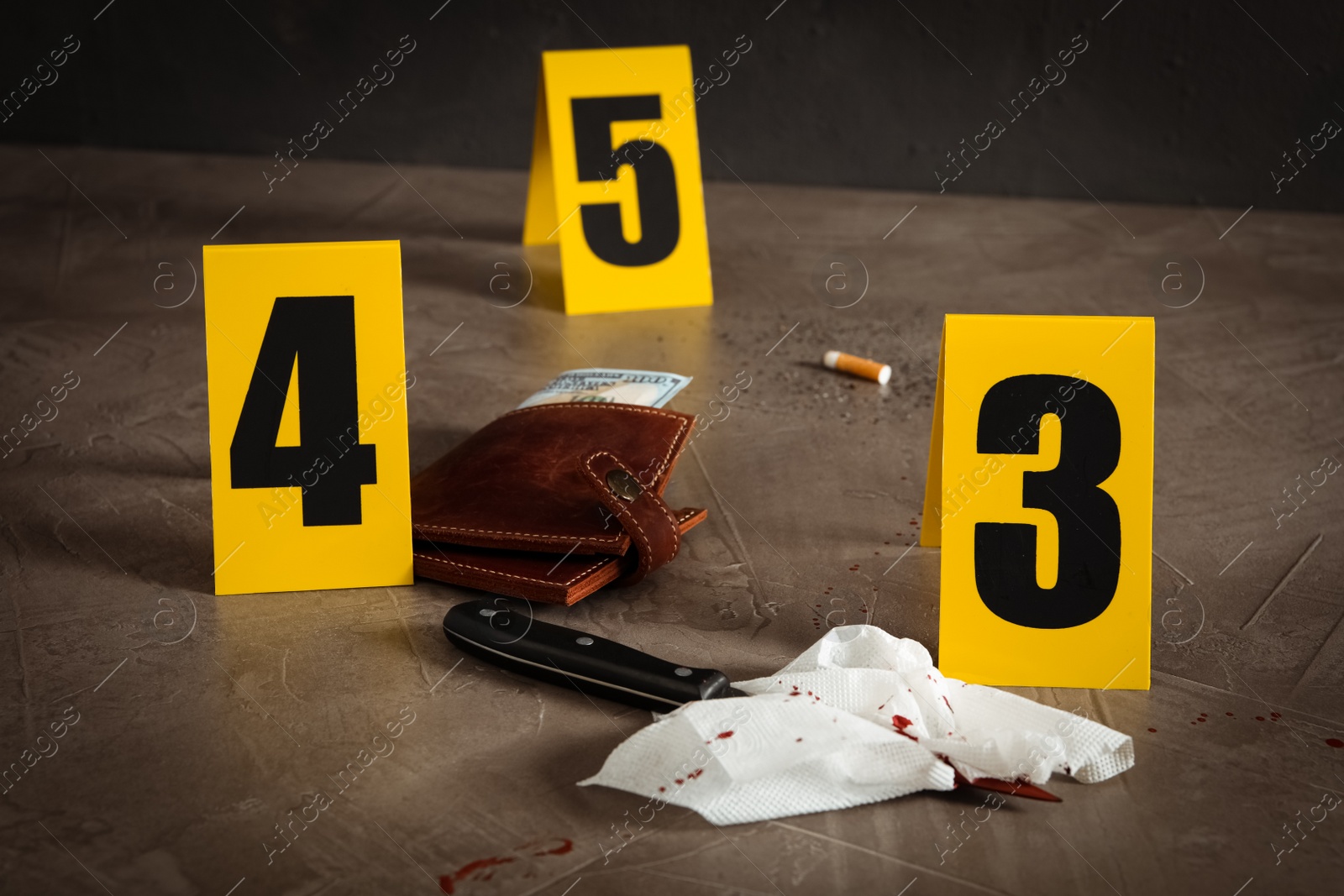 Photo of Knife, wallet and bloody napkin on grey stone table at crime scene
