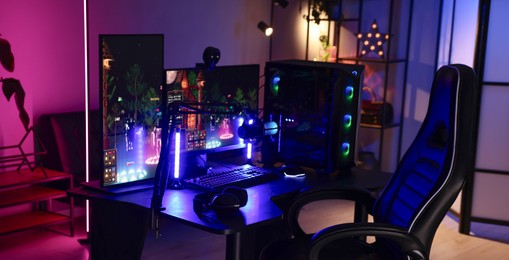 Playing video games. Stylish room interior with modern computer and gaming chair in neon lights