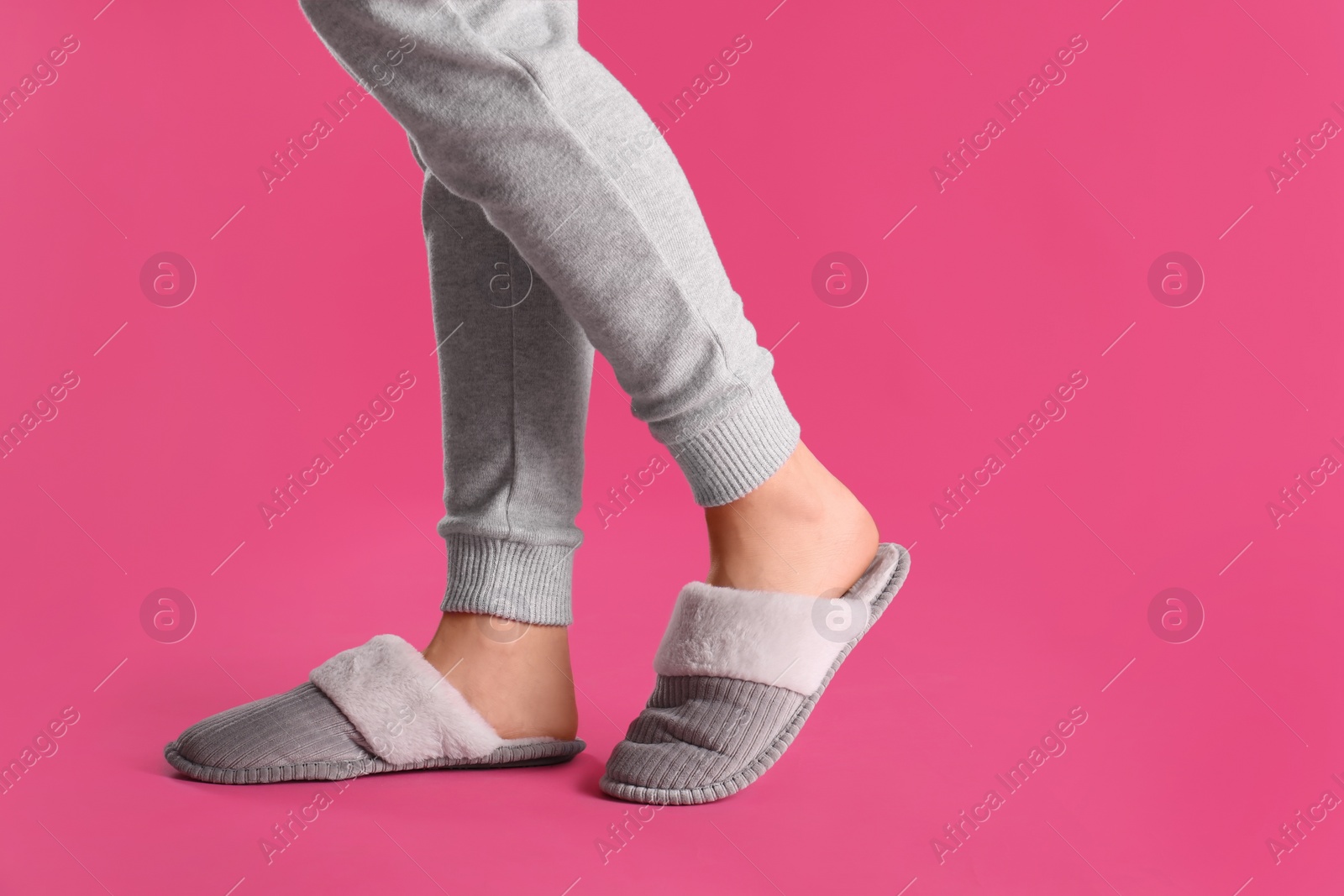 Photo of Woman in warm soft slippers on pink background, closeup