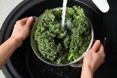 Photo of Woman washing fresh kale leaves over sink, closeup