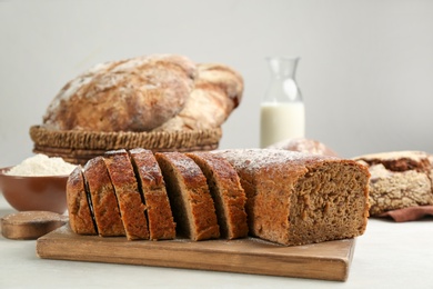 Photo of Cut freshly baked bread on white wooden table