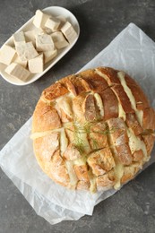 Freshly baked bread with tofu cheese on grey table, flat lay