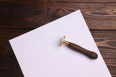 Photo of One stamp tool and sheet of paper on wooden table, top view. Space for text