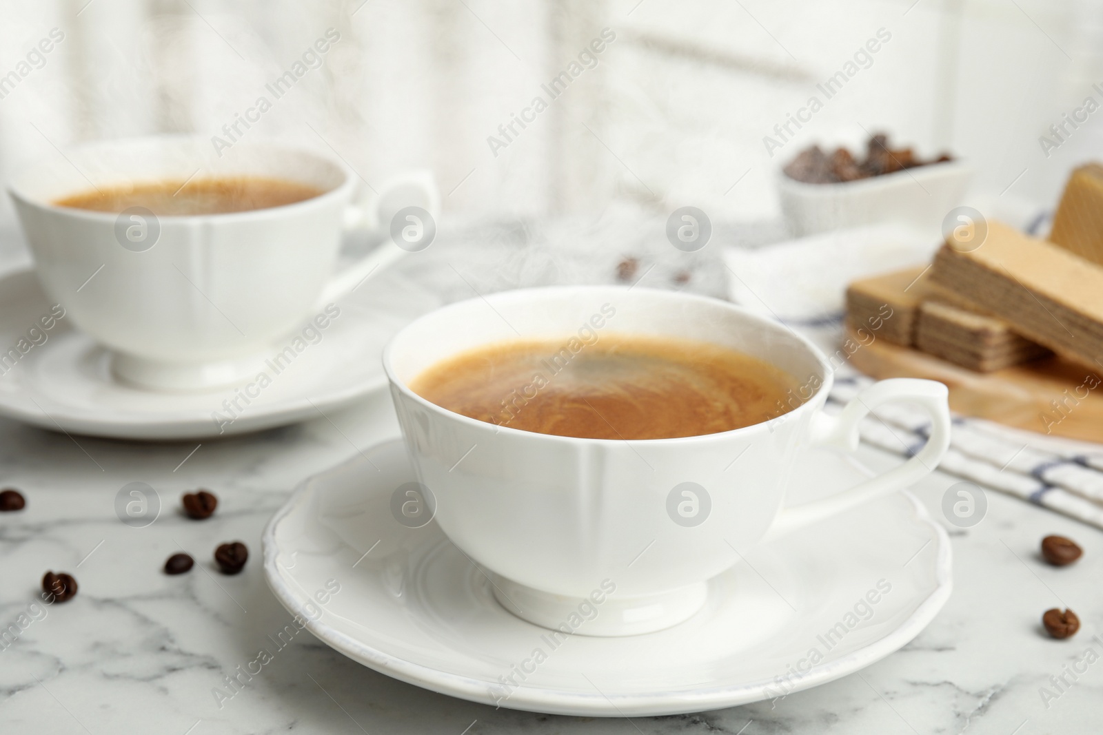 Photo of Delicious coffee and wafers for breakfast on white marble table