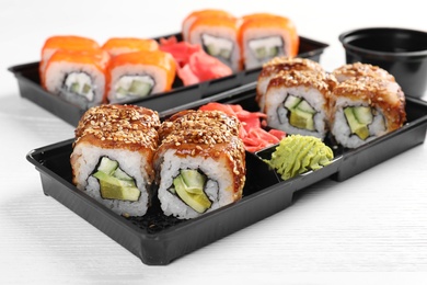 Boxes with tasty sushi rolls on white table. Food delivery