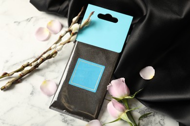 Photo of Scented sachet, roses and black fabric on white marble table