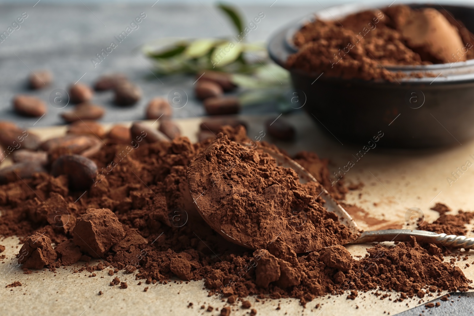 Photo of Spoon and pile of cocoa powder on table