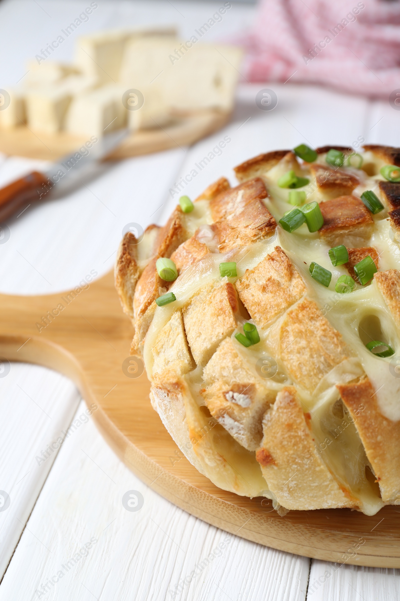 Photo of Freshly baked bread with tofu cheese and green onions on white wooden table, closeup