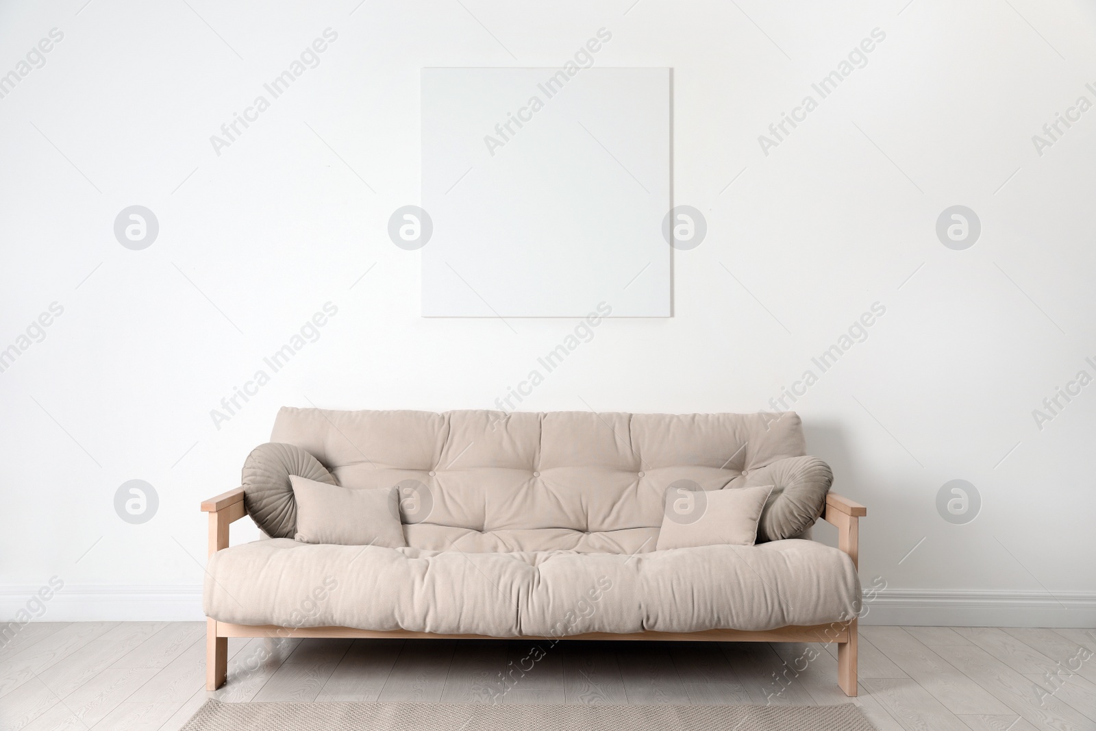 Photo of Blank canvas on wall over beige sofa indoors. Space for design