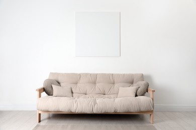 Blank canvas on wall over beige sofa indoors. Space for design