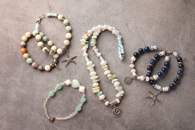 Photo of Different beautiful bracelets and necklace with gemstones on grey background, flat lay