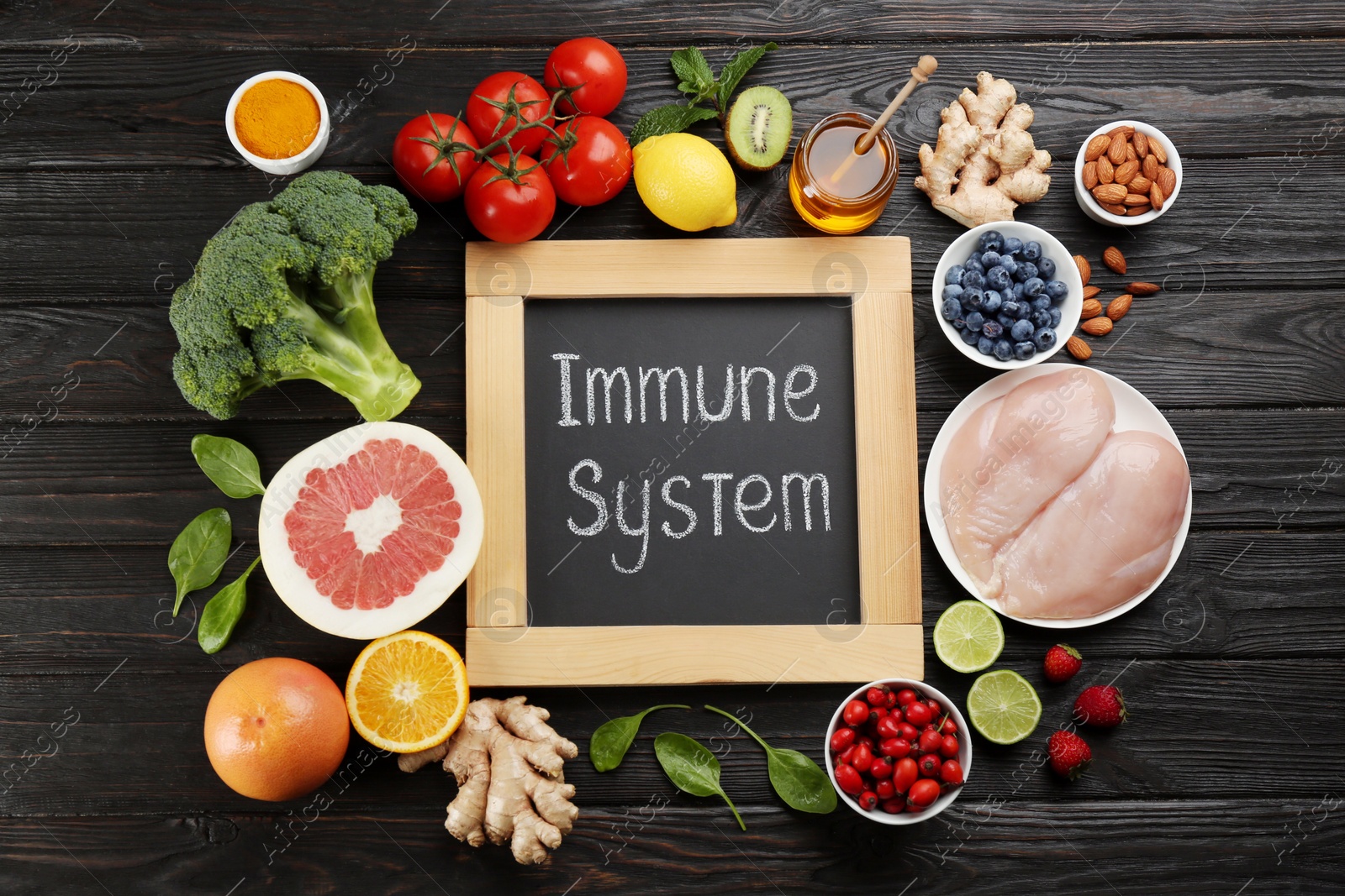 Photo of Chalkboard with phrase Immune System and fresh products on dark wooden table, flat lay