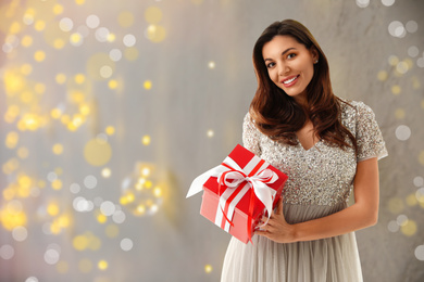 Image of Beautiful woman with Christmas gift on blurred background. Space for text