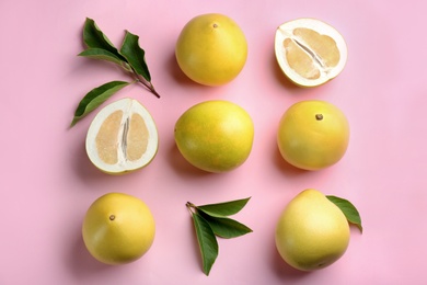 Photo of Fresh cut and whole pomelo fruits with leaves on pink background, flat lay