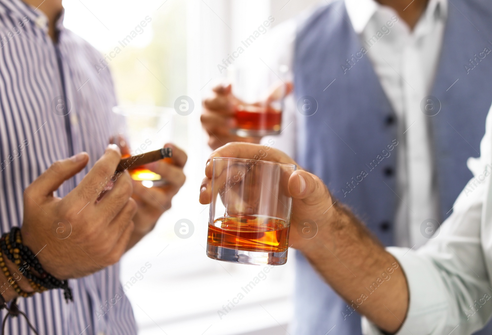 Photo of Group of friends drinking whiskey together indoors, closeup