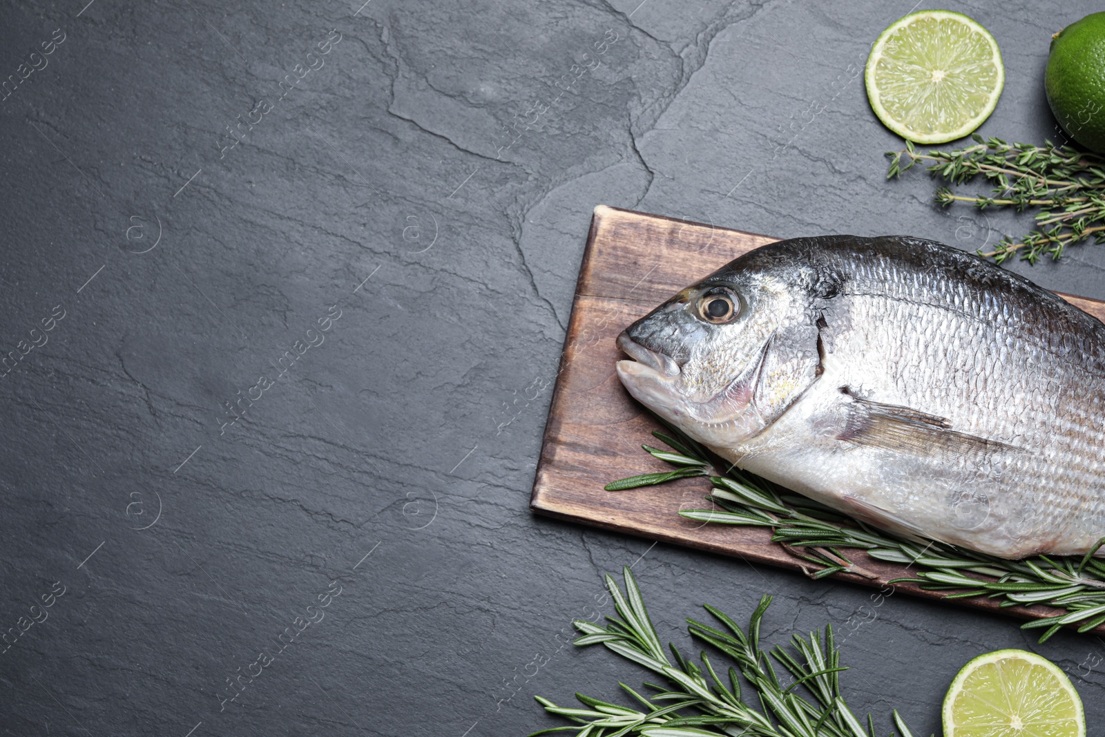 Photo of Flat lay composition with fresh raw dorado fish and ingredients on black table, space for text