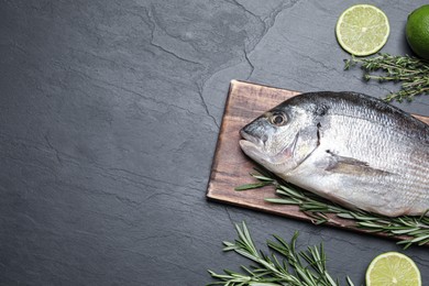 Photo of Flat lay composition with fresh raw dorado fish and ingredients on black table, space for text