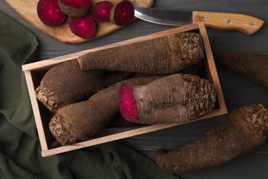 Photo of Wooden crate with whole, cut red beets and knife on table, flat lay