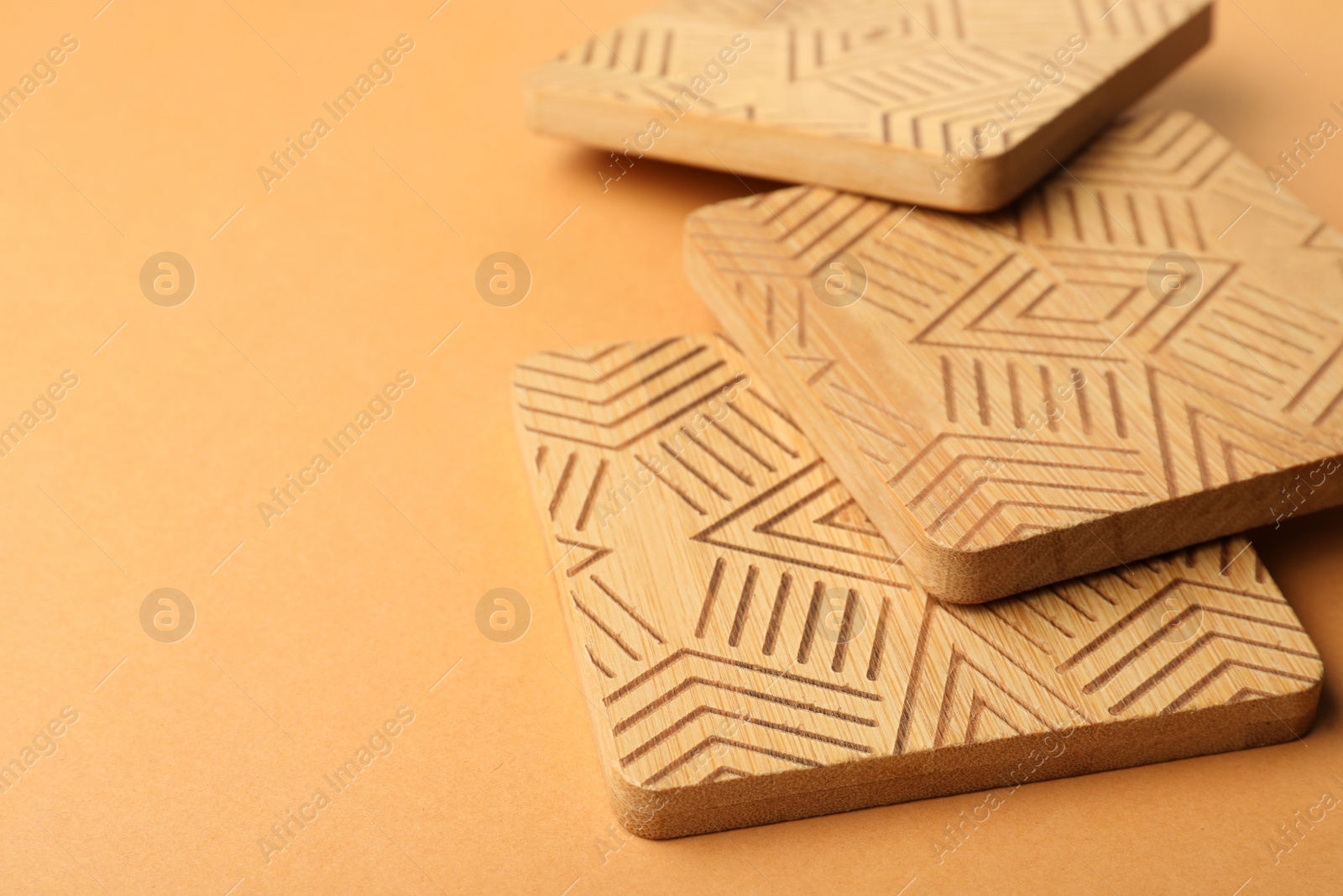 Photo of Stylish wooden cup coasters on orange background, space for text