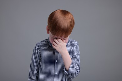 Photo of Sad little boy crying on grey background