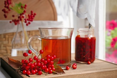 Helpful viburnum berries and drink on wooden board indoors