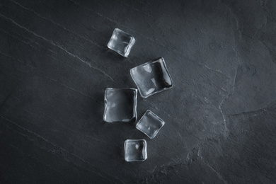 Photo of Crystal clear ice cubes on black table, flat lay