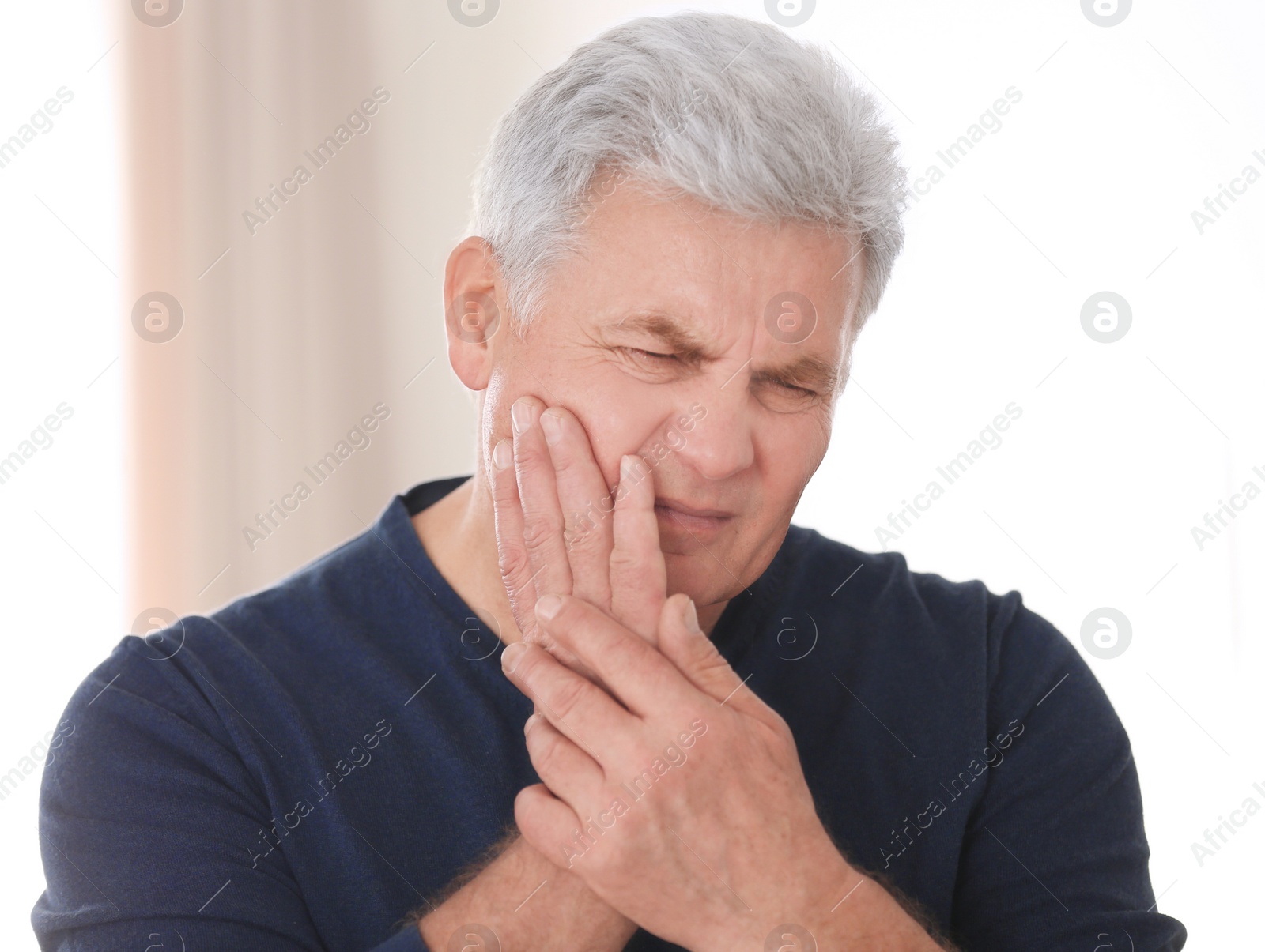 Photo of Mature man suffering from toothache at home