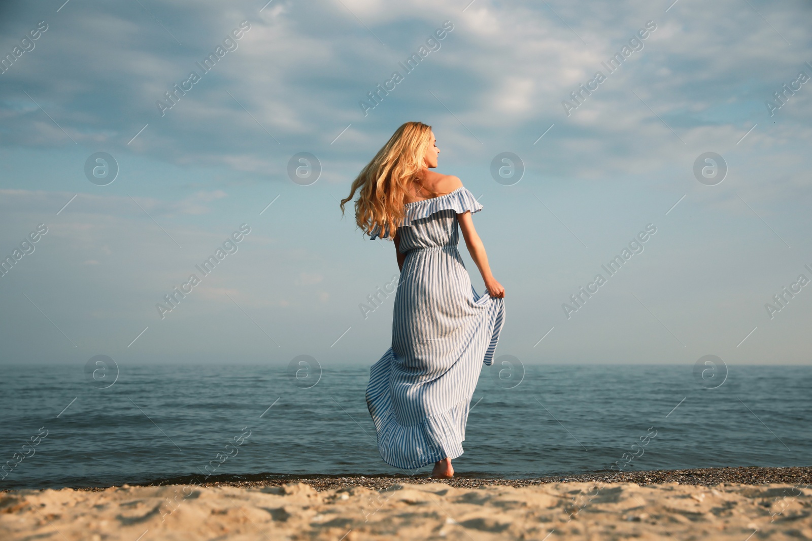 Photo of Beautiful young woman on sea beach, back view