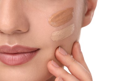 Woman with swatches of foundation on face against white background, closeup