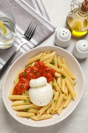 Photo of Delicious pasta with burrata cheese and sauce served on light grey table, flat lay