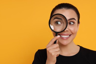 Photo of Woman looking through magnifier glass on yellow background, space for text