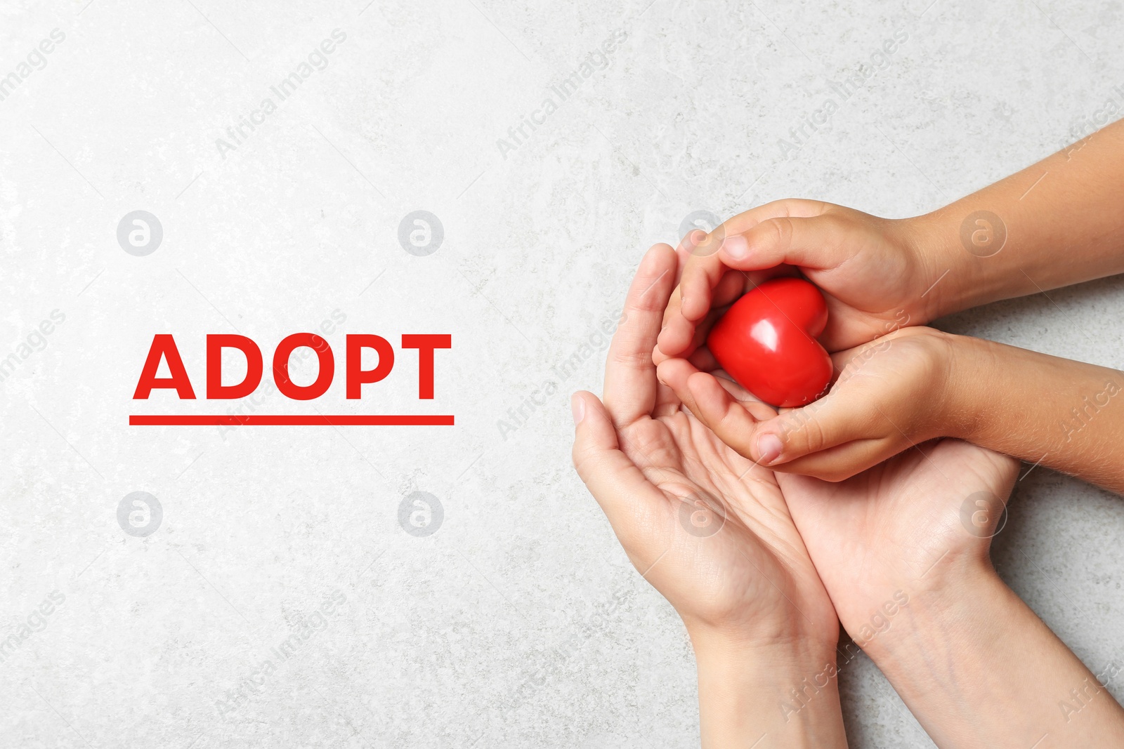 Image of Woman and child holding heart on grey stone background, top view. Adoption concept