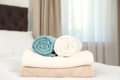 Photo of Soft clean terry towels on bed in room