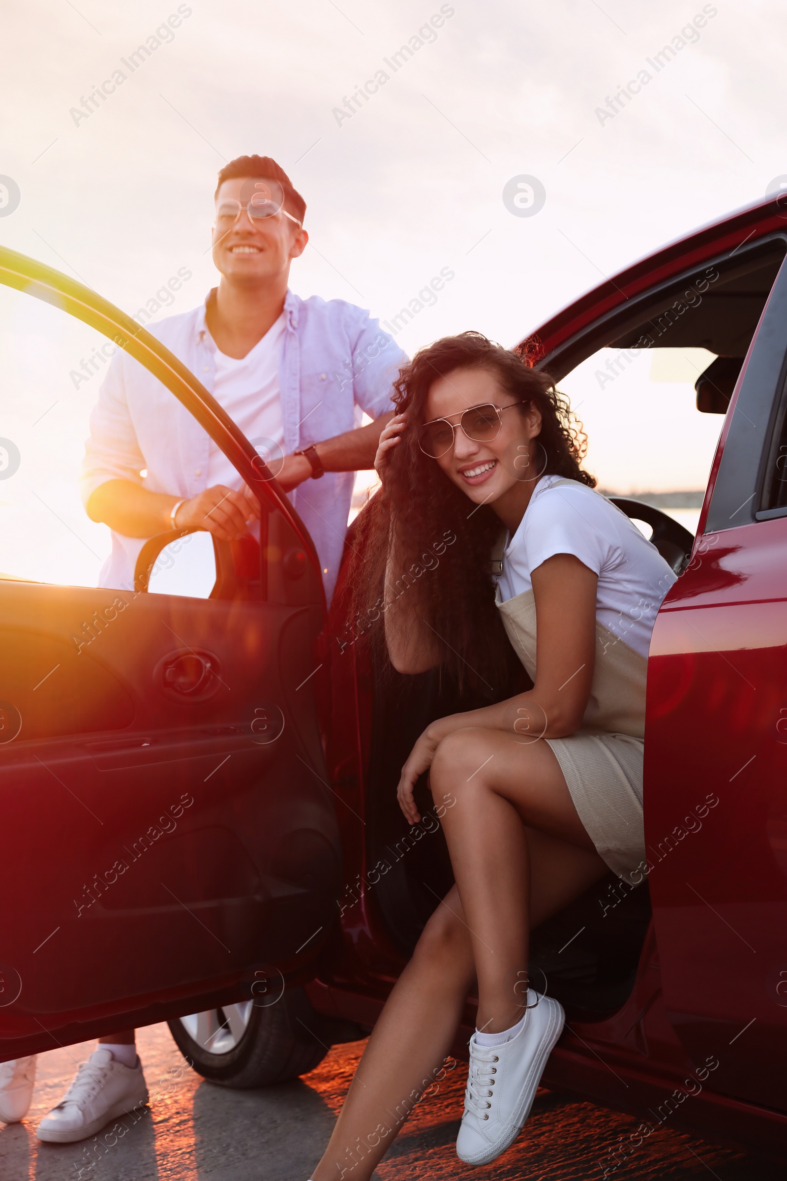 Photo of Happy couple near car outdoors at sunset. Summer trip