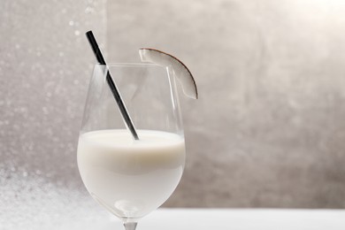 Glass of delicious coconut milk on light background, space for text