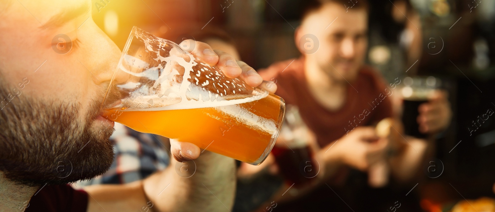 Image of Young man drinking tasty beer in pub, space for text. Banner design