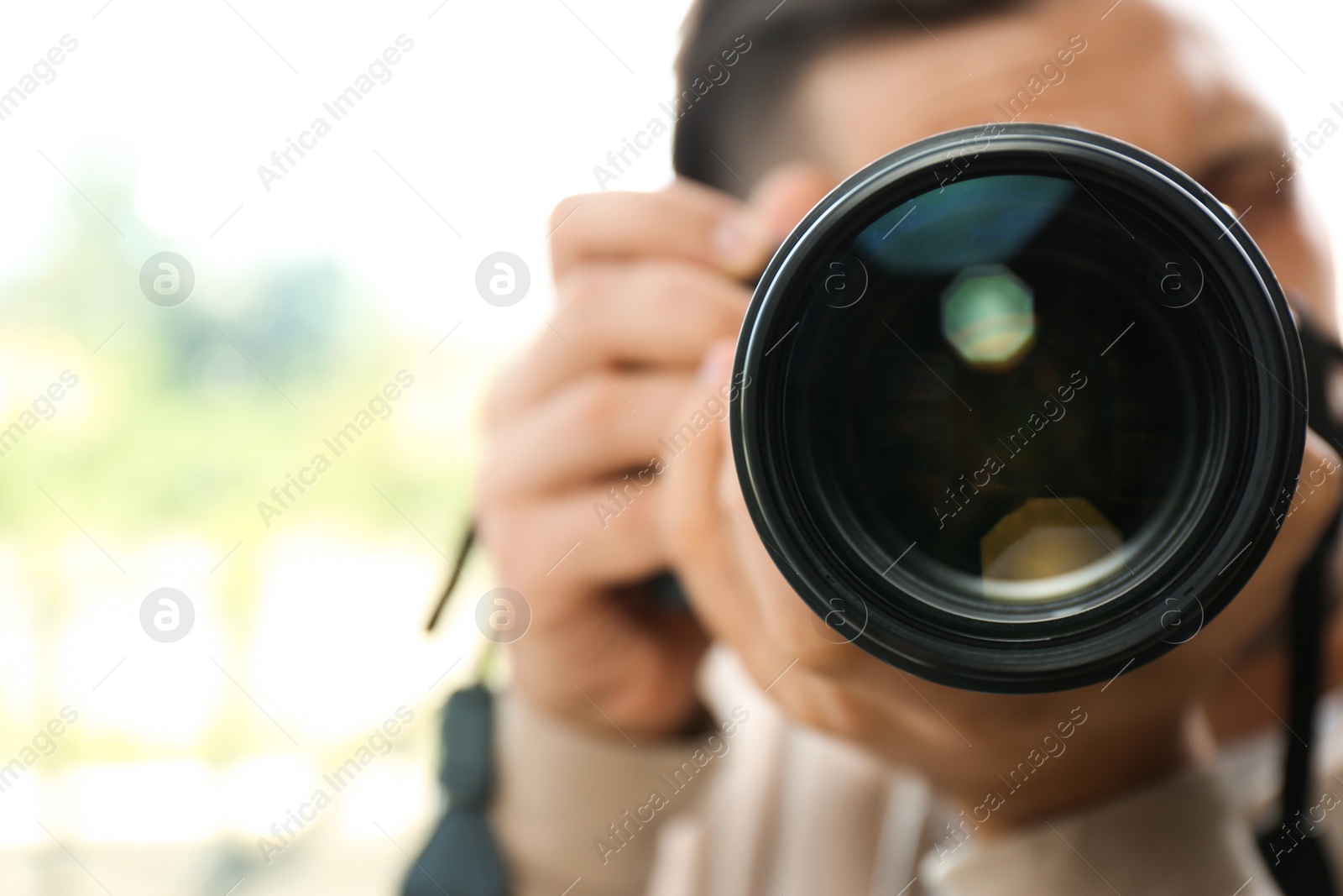 Photo of Male photographer with professional camera on blurred background. Space for text