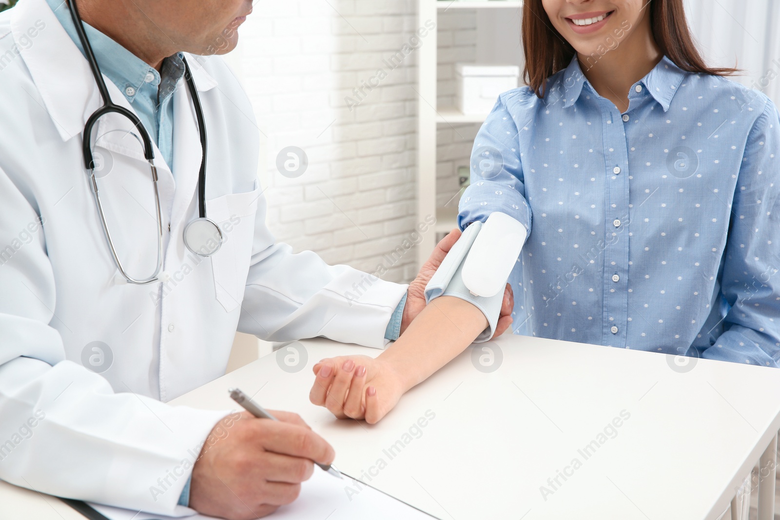 Photo of Doctor checking young woman's pulse with medical device in hospital, closeup