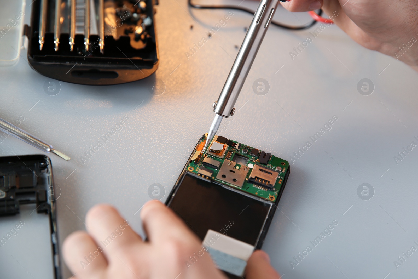 Photo of Technician repairing mobile phone at table, closeup