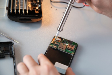 Technician repairing mobile phone at table, closeup