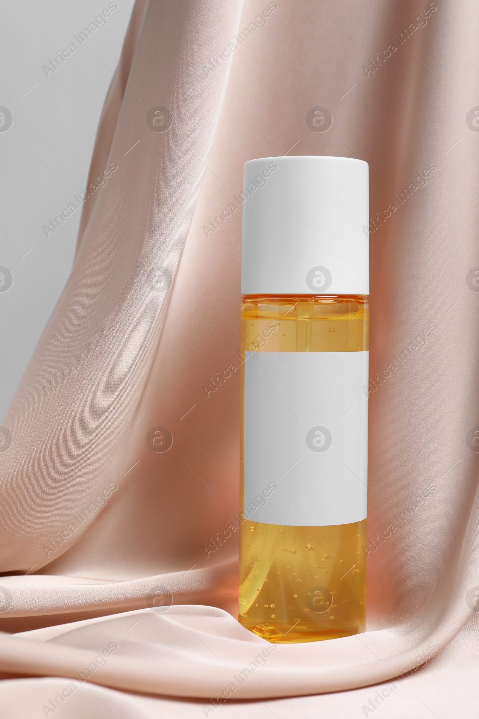 Photo of Bottle of cosmetic product on pink fabric